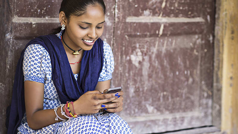 Indian woman smiling while using her mobile phone. 