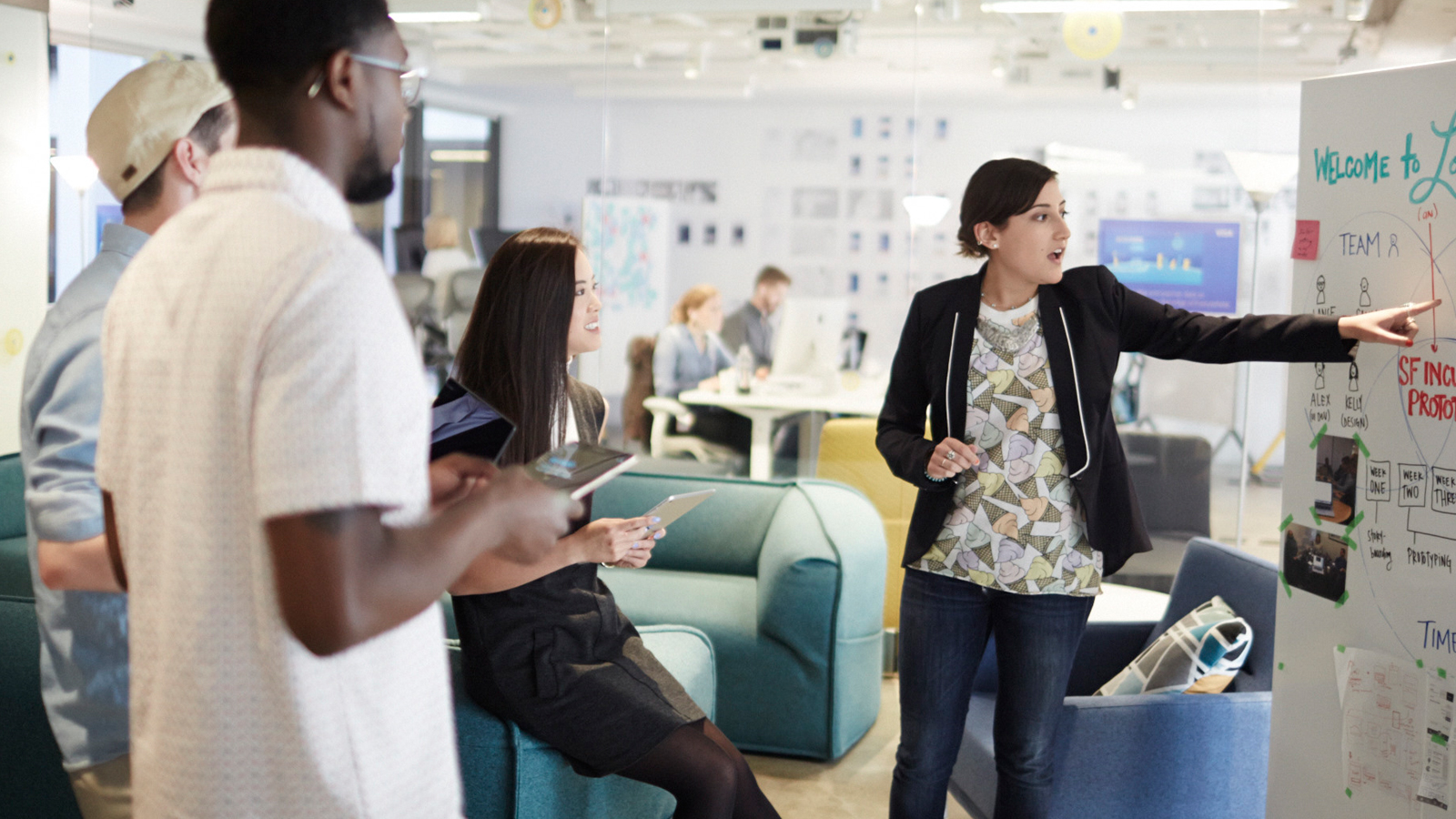 People having a discussion in front of an idea board. People having a discussion in front of an idea board.