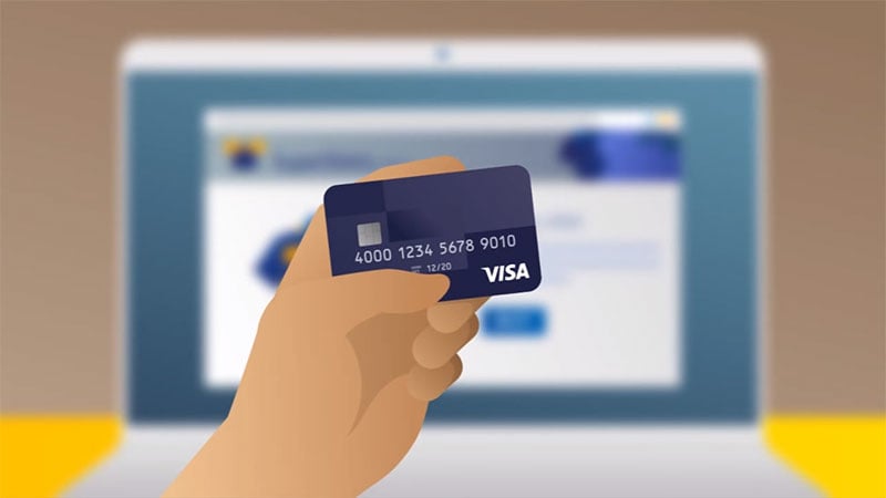 A hand holding a Visa card in front of a laptop screen, to symbolise secure online shopping payment methods