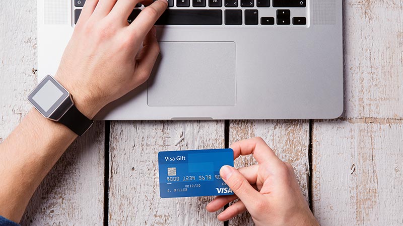person-using-laptop-and-holding-visa-card-800x450